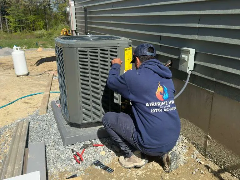 AirPrime technician in branded uniform servicing an outdoor condenser unit